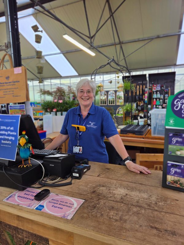 Smiling woman stands behind the till at Mayfield Garden Centre's shop